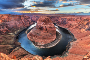 Horseshoe Bend at sunset with the Colorado River curving around red sandstone cliffs.