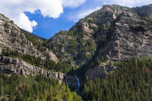 Bridal Veil Falls cascading down limestone cliffs in Provo Canyon, Utah, surrounded by pine forest.
