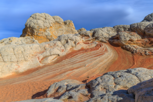 White Pocket sandstone ridge with sweeping red and white striations beneath textured rock formations.