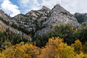 Upper Falls in Provo Canyon, Utah, with a narrow waterfall dropping between rugged cliffs and autumn-colored trees.