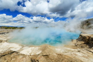 Steaming hot spring with turquoise water in Yellowstone National Park under cloudy sky