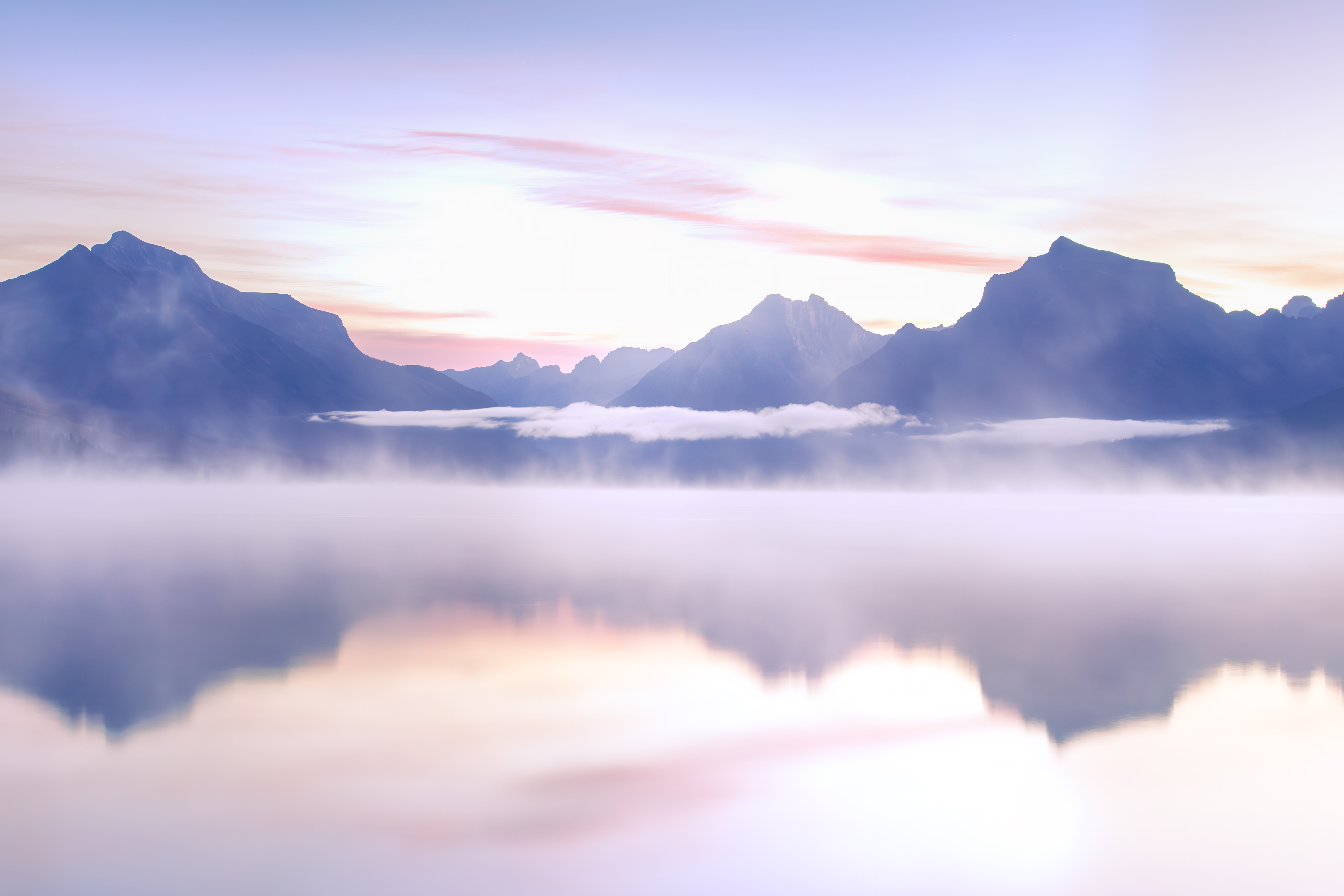 Soft sunrise light and fog over Lake McDonald with mountain silhouettes, Glacier National Park landscape photography