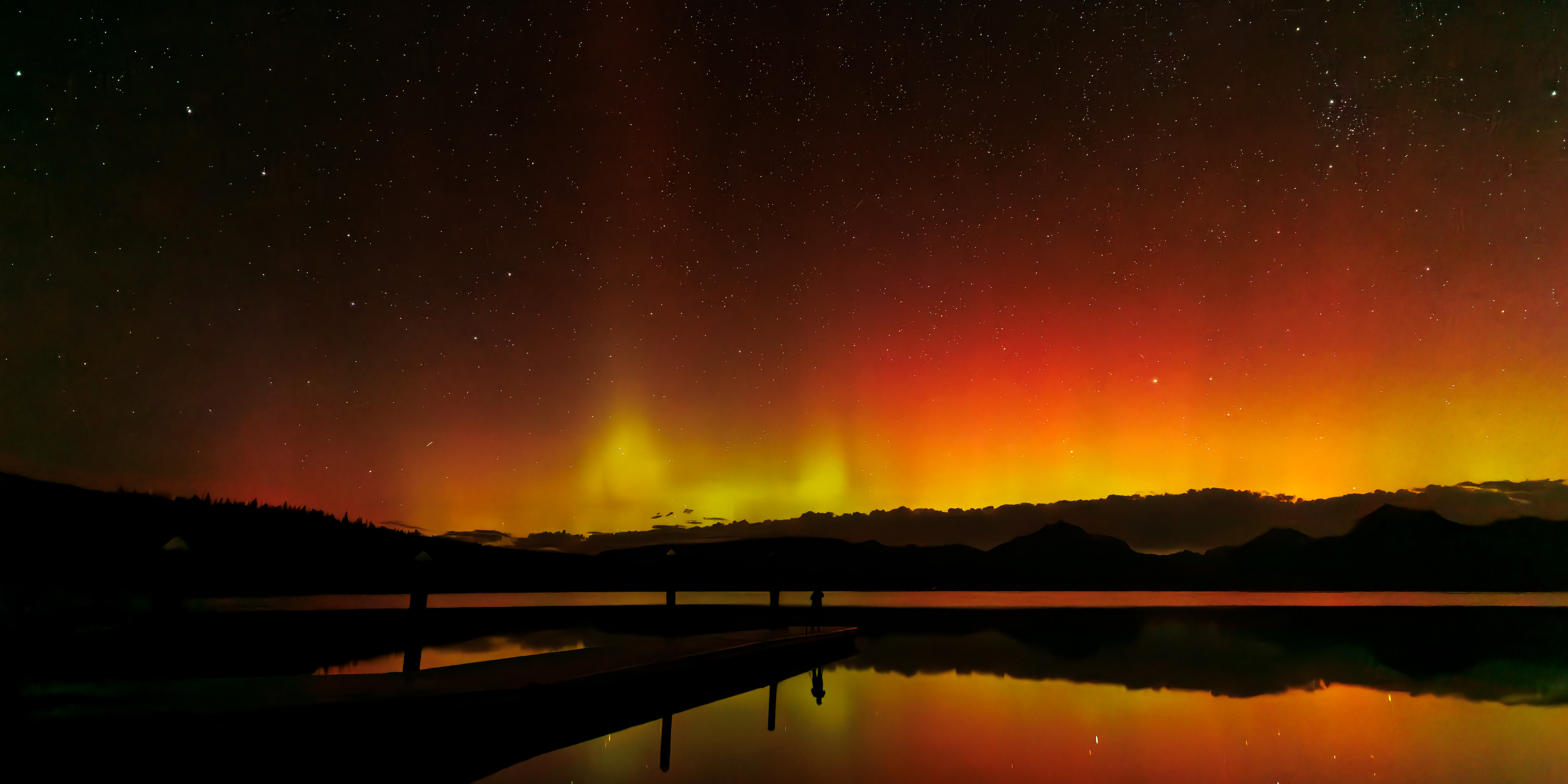 Northern Lights glowing red and green above Lake McDonald at night, Glacier National Park landscape photography