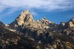 Grand Teton peak rising above forested slopes under a clear blue sky, Grand Teton National Park landscape photography