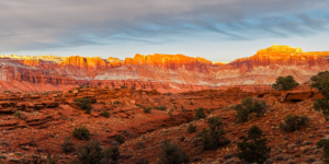 Sunset over Capitol Reef National Park with glowing red cliffs and dramatic desert landscape, fine art Utah photography.